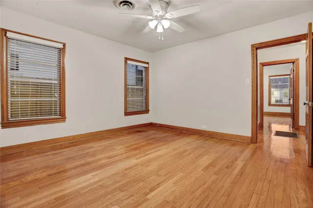 a view of empty room with wooden floor and fan