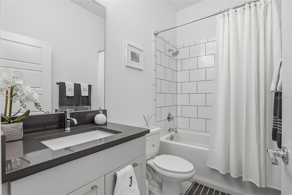 4810 West McElroy Avenue, Unit 30 Tampa, FL 33611 - Photo 31 of 43 a bathroom with a granite countertop sink mirror vanity and toilet