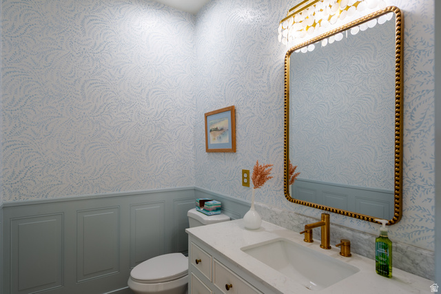 868 Braddock Lane Alpine, UT 84004 - Photo 26 of 64 Powder room featuring a vanity with a white countertop and integrated sink, gold-toned faucet, and a gold-framed mirror