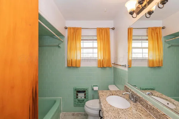 a bathroom with a granite countertop toilet sink and mirror