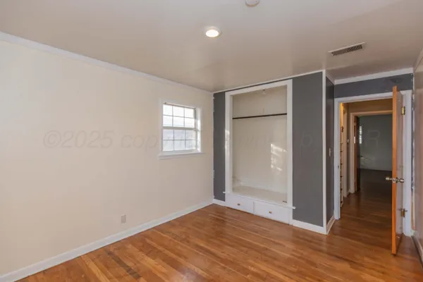 a view of an empty room with wooden floor and closet