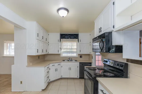 a kitchen with stainless steel appliances granite countertop a stove a sink and white cabinets