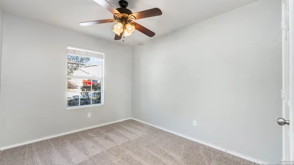 an empty room with a window and a fan