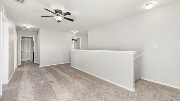 wooden floor in an empty room with a chandelier fan