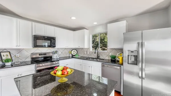 a kitchen with stainless steel appliances granite countertop a refrigerator a stove and a sink