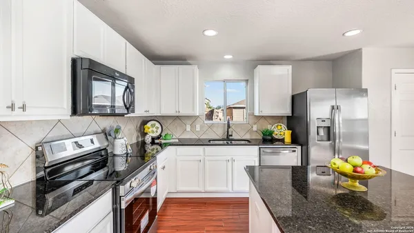 a kitchen with stainless steel appliances granite countertop a stove top oven a sink and cabinets
