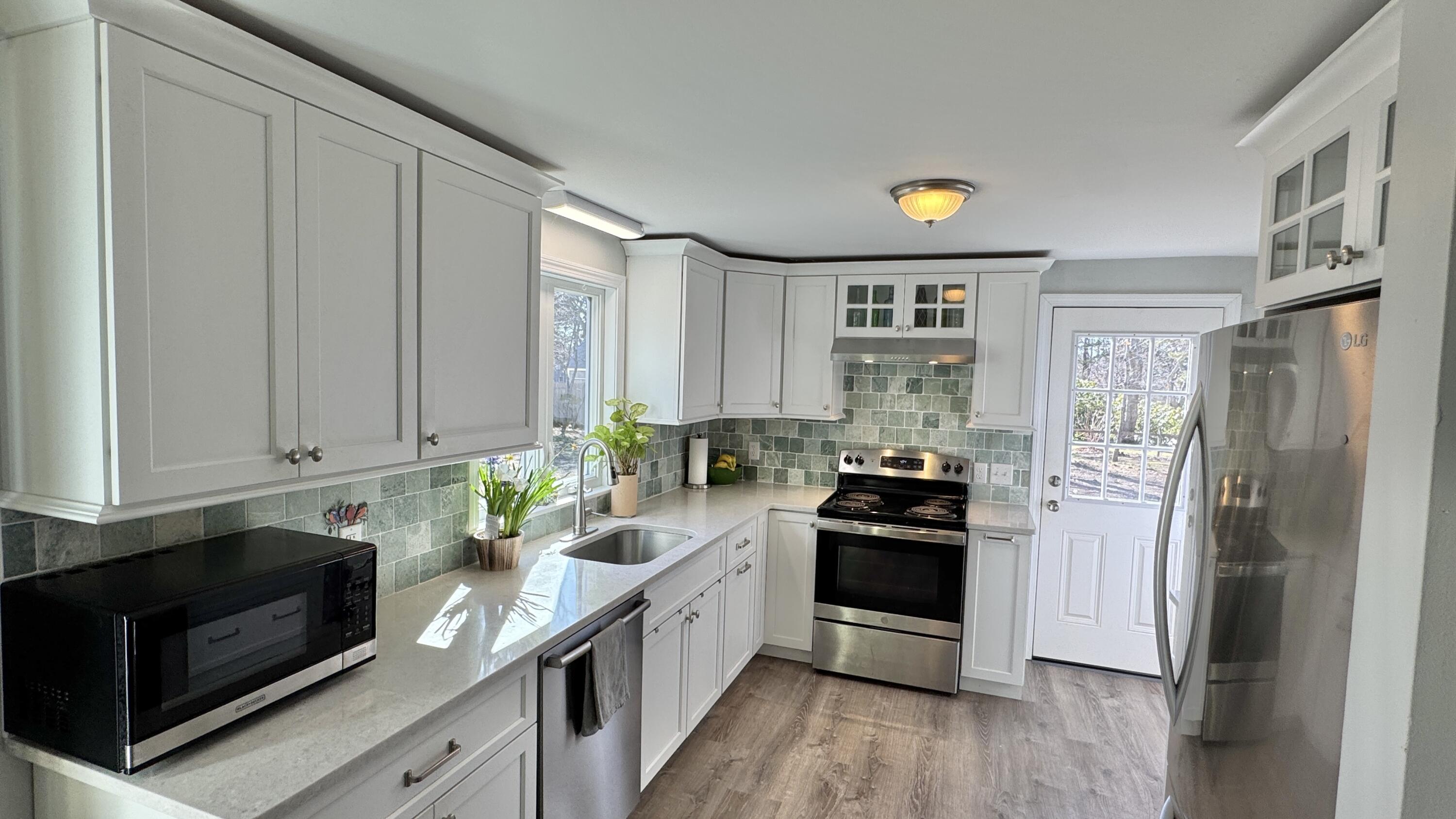 300 Brackett Road Eastham, MA 02642 - Photo 6 of 30 a kitchen with a refrigerator a stove a sink and wooden floor