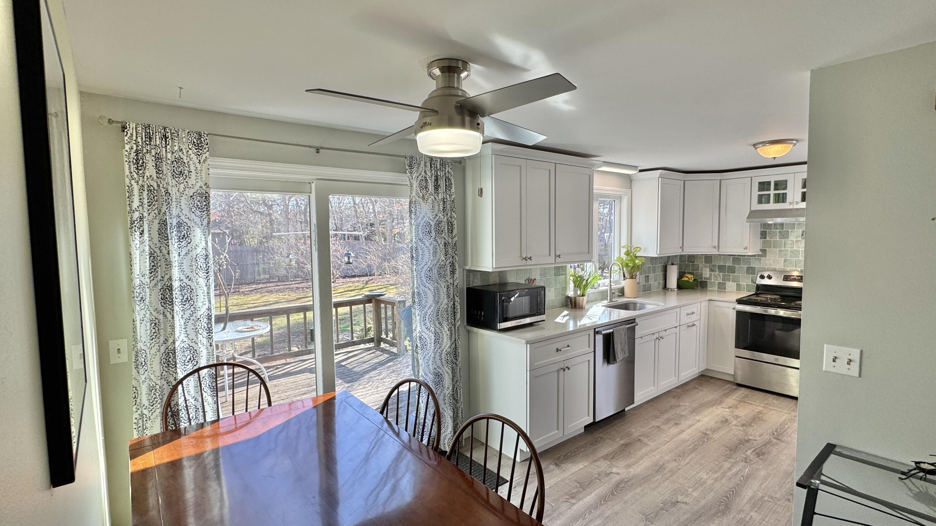 300 Brackett Road Eastham, MA 02642 - Photo 10 of 30 a kitchen with stainless steel appliances granite countertop a stove top oven a refrigerator a sink dishwasher and white cabinets with wooden floor