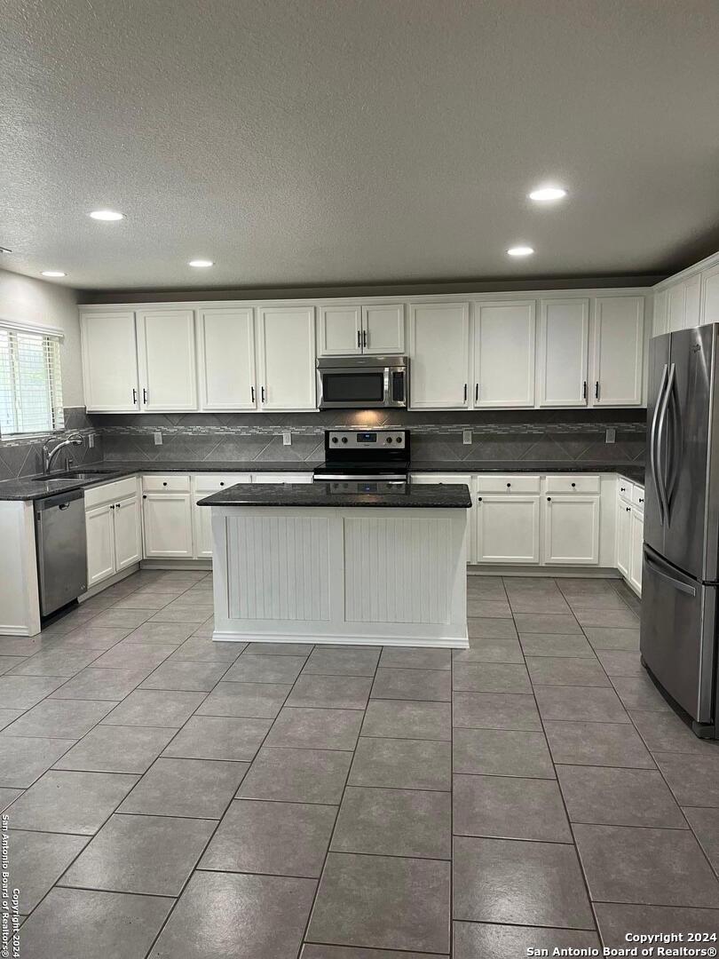 803 Roping Horse San Antonio, TX 78260 - Photo 5 of 18 a kitchen with stainless steel appliances granite countertop a sink and white cabinets