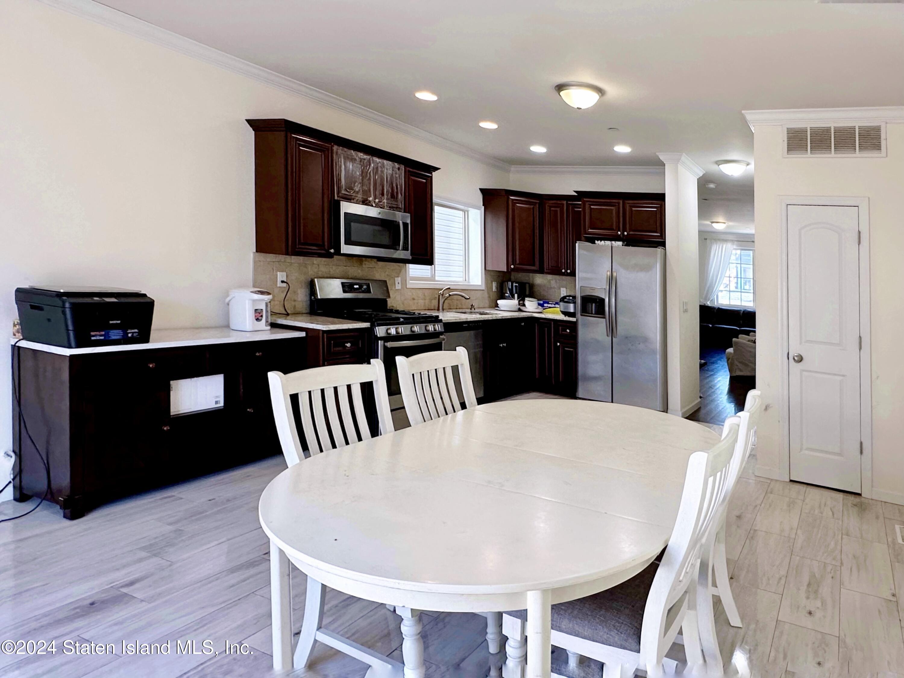 94 Catherine Street Staten Island, NY 10302 - Photo 19 of 33 a kitchen with stainless steel appliances granite countertop a refrigerator a stove a sink a dining table and chairs