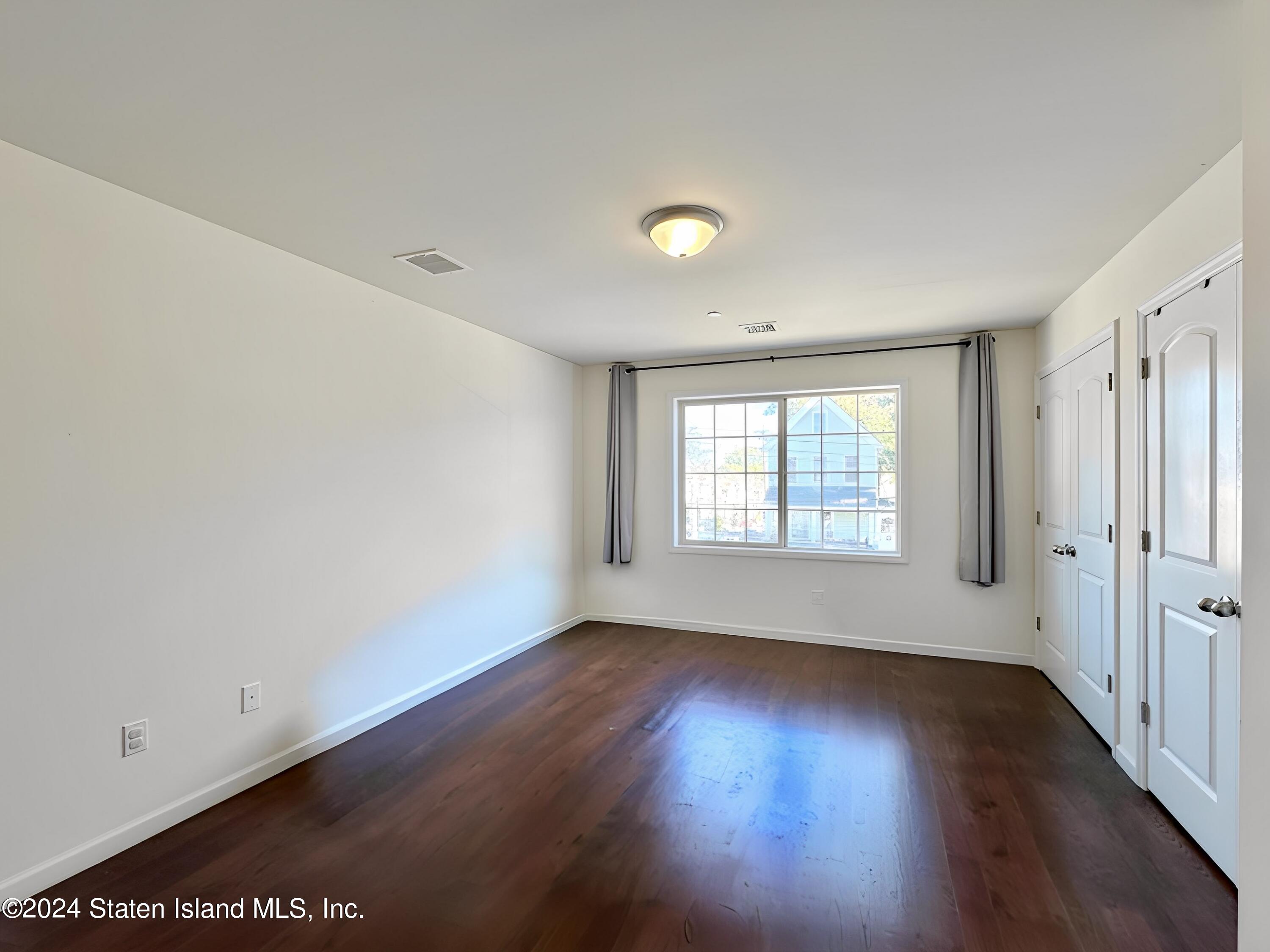 94 Catherine Street Staten Island, NY 10302 - Photo 22 of 33 an empty room with wooden floor and windows