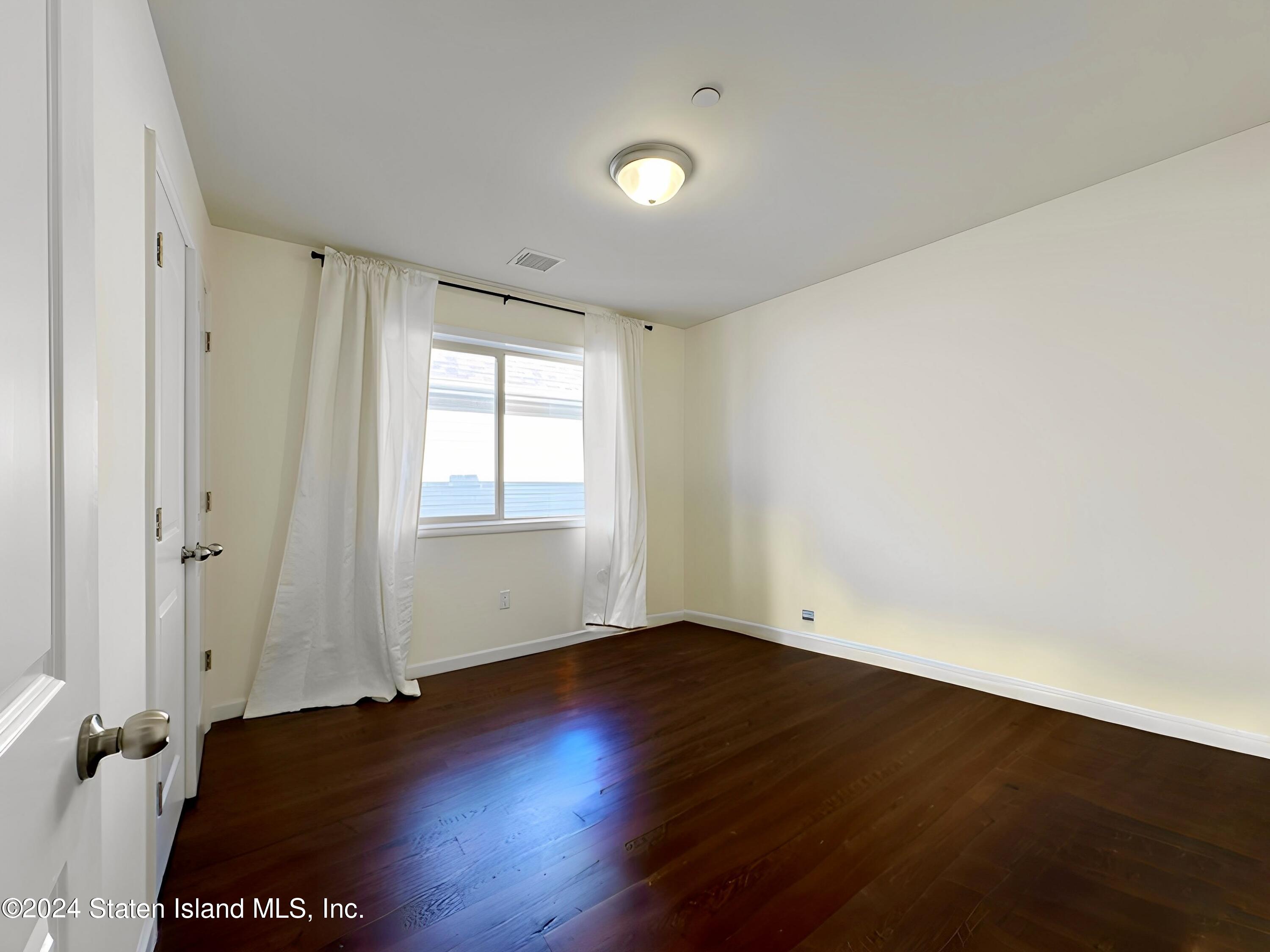 94 Catherine Street Staten Island, NY 10302 - Photo 24 of 33 an empty room with wooden floor and windows