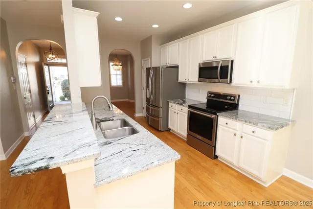 a kitchen with granite countertop a refrigerator stove microwave and sink