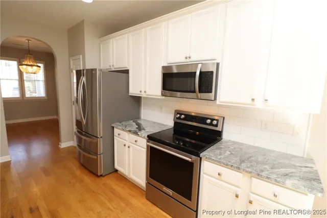 a kitchen with granite countertop a sink and a white wooden cabinets