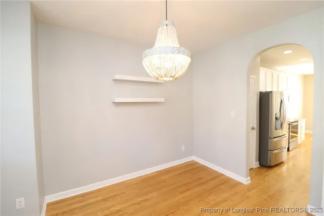 a view of empty room with wooden floor and kitchen