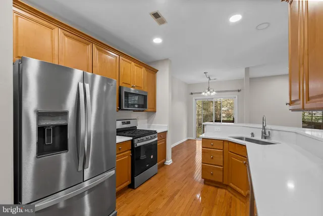 a kitchen with stainless steel appliances granite countertop a refrigerator a sink dishwasher a stove and a sink