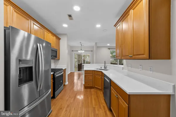 a kitchen with stainless steel appliances granite countertop a refrigerator a sink dishwasher a oven with large countertops and wooden floor