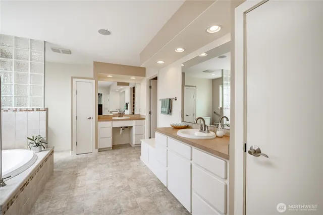 a bathroom with a granite countertop tub sink and mirror