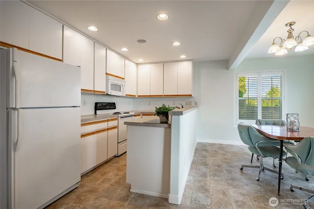 a kitchen with stainless steel appliances kitchen island granite countertop a dining table chairs and a refrigerator