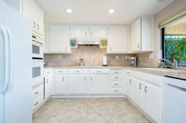 a kitchen with granite countertop white cabinets white stainless steel appliances with a sink and dishwasher
