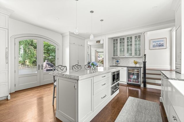 a kitchen with stainless steel appliances granite countertop a stove a sink dishwasher a refrigerator and a dining table with wooden floor