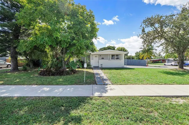 a view of a house with a yard and large tree