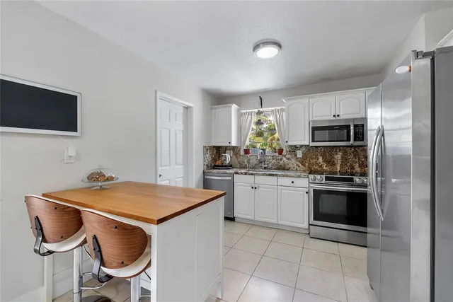 a kitchen with stainless steel appliances granite countertop a table chairs sink and cabinets