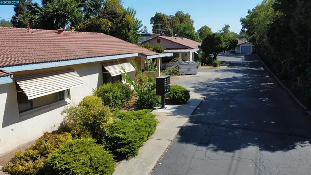 a view of a patio with table and chairs under an umbrella with large trees