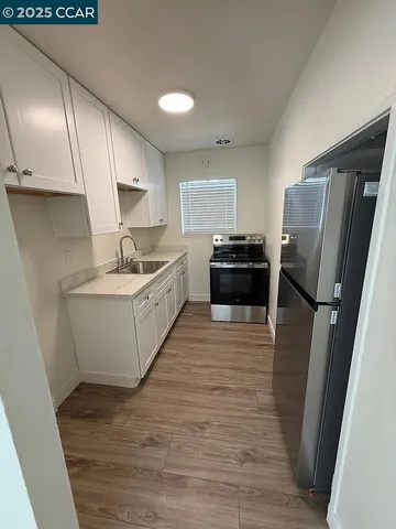 a kitchen with a sink a refrigerator and cabinets