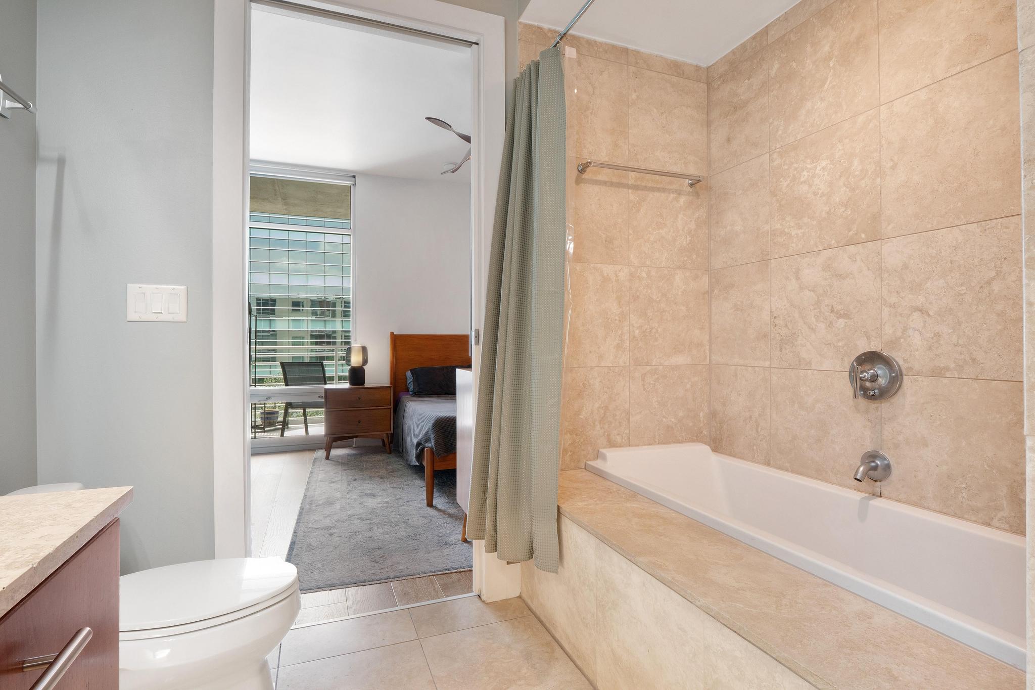 210 Lee Barton Drive, Unit 415 Austin, TX 78704 - Photo 9 of 22 Bathroom with tile patterned floors, shower / bath combo with shower curtain, vanity, and toilet