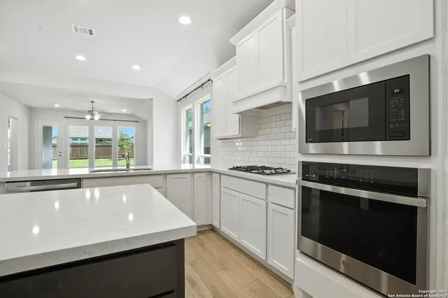 a large kitchen with stainless steel appliances granite countertop a stove and a microwave