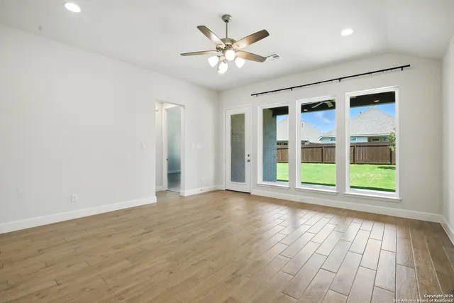 a view of an empty room with a window and wooden floor