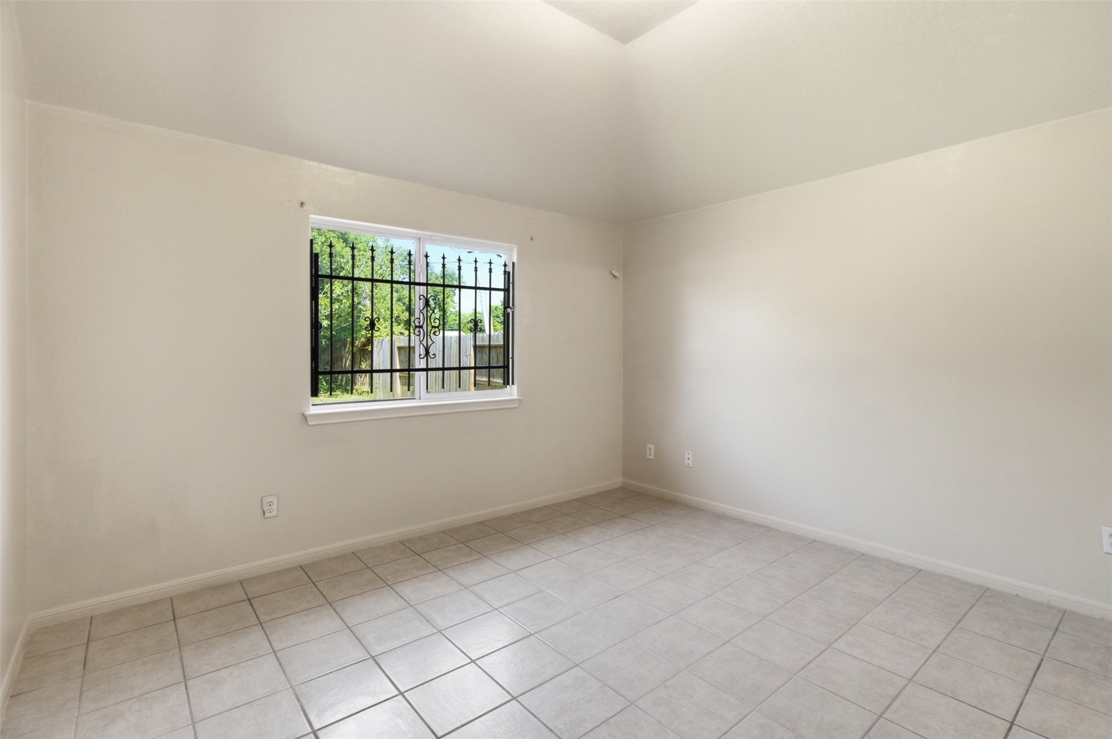 15738 Boonridge Road Houston, TX 77053 - Photo 17 of 31 Bright and airy room with neutral tile flooring, high ceiling, and a window featuring decorative ironwork, allowing plenty of natural light.