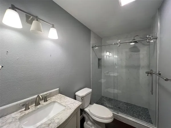 a bathroom with a granite countertop sink toilet and shower