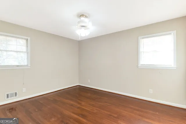 an empty room with wooden floor and windows