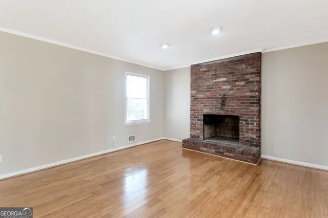 an empty room with wooden floor and fireplace
