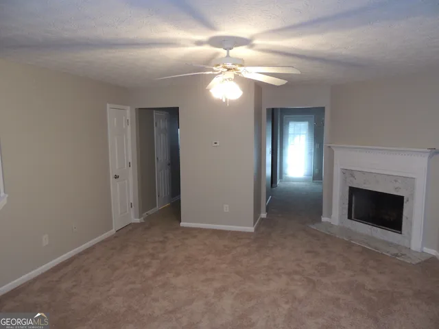 a view of an empty room with chandelier fan and fire place