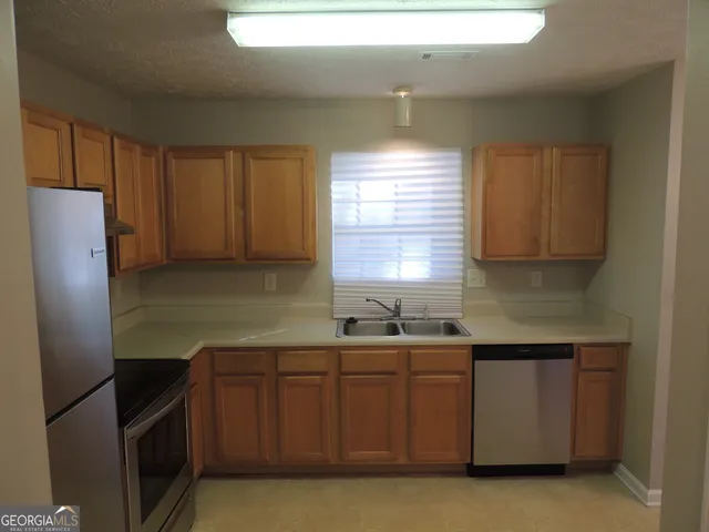 a kitchen with stainless steel appliances granite countertop a sink a refrigerator and a stove