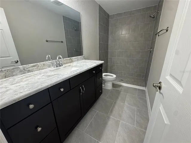 a bathroom with a granite countertop sink toilet and shower