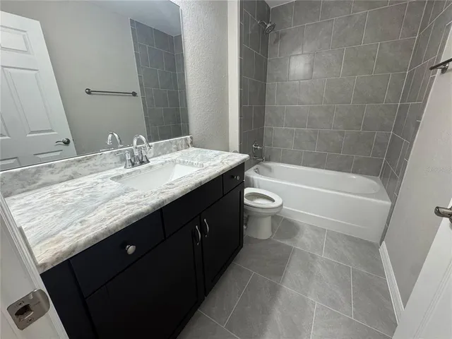 a bathroom with a granite countertop bathtub sink vanity mirror and toilet