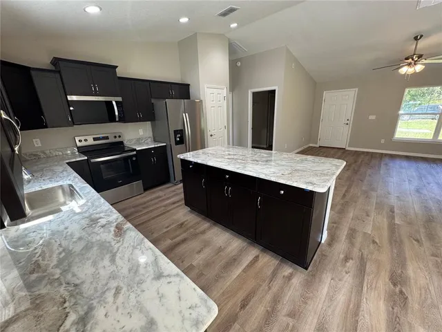 a large kitchen with granite countertop a sink and a stove top oven with wooden floor