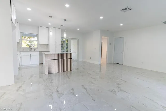 a large white kitchen with kitchen island a sink a stove and a refrigerator with cabinets