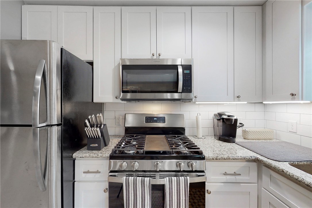 513 Boyett Street, Unit 2 College Station, TX 77840 - Photo 7 of 22 a kitchen with stainless steel appliances granite countertop a stove a refrigerator and a white cabinets