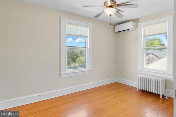 an empty room with wooden floor closet and windows