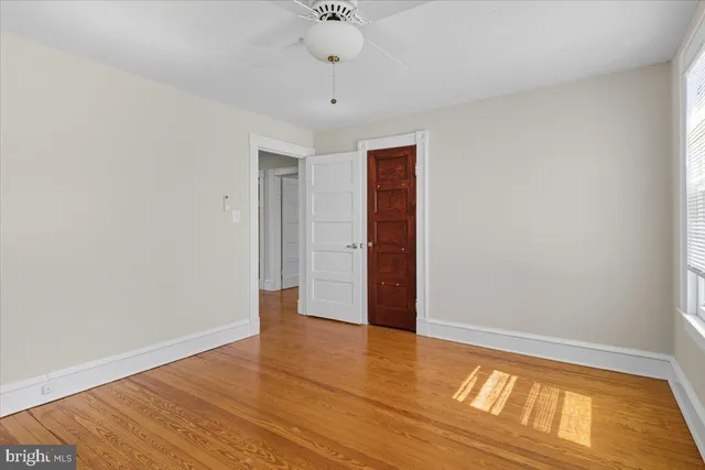 a view of an empty room with window and wooden floor
