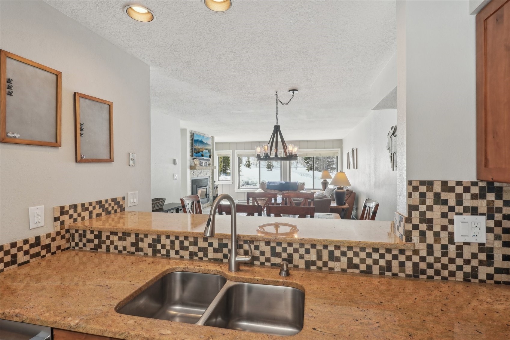 1944 Soda Ridge Road, Unit 1228 Keystone, CO 80435 - Photo 15 of 46 Kitchen featuring a sink, a textured ceiling, a glass covered fireplace, a notable chandelier, and backsplash