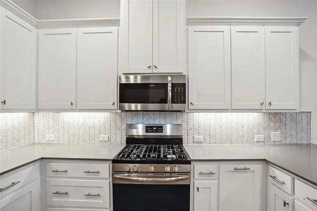 a kitchen with granite countertop a stove a sink and dishwasher with white cabinets
