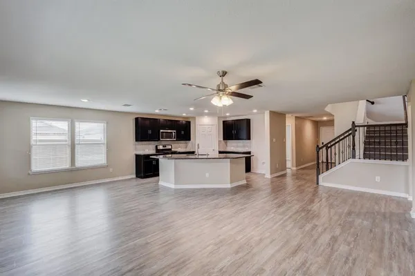 a view of kitchen with microwave a refrigerator and wooden floor