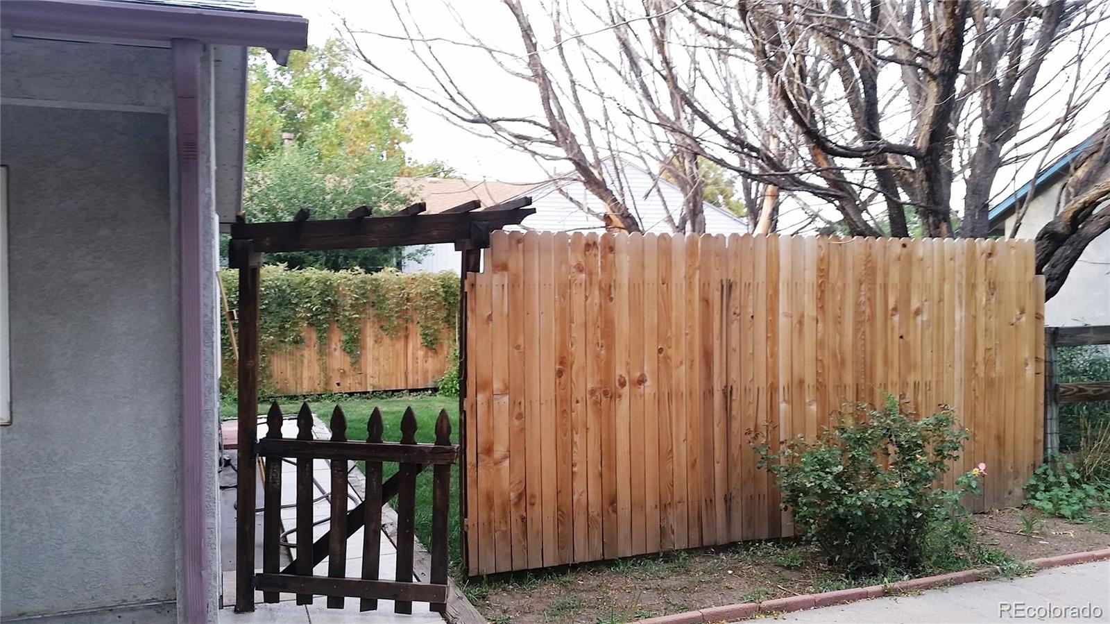 1910 South Decatur Street, Unit C Denver, CO 80219 - Photo 3 of 15 a view of a backyard with large trees and wooden fence