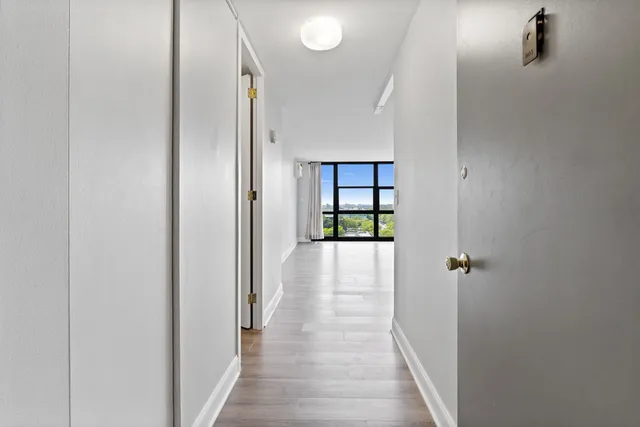 a view of a hallway with wooden floor and a bathroom